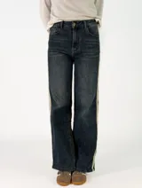 Pantalon recto bicolor con frente en denim azul y espalda en denim negro, presenta franjas laterales en tono claro y cierre frontal con botones.