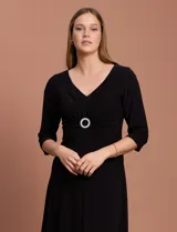 Vestido midi negro de RM Richards en seda fría, con escote en V, mangas 3/4, frunce en la delantera y aplique circular de brillos en el centro.