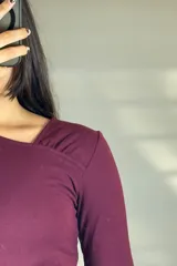 Remera de manga larga color bordó con diseño de escote asimétrico y detalle de solapa diagonal en el pecho.