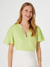 Blusa verde con estampado geométrico blanco, cuello en V y mangas cortas amplias.