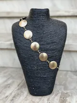 Cinto dorado de metal con eslabones y monedas circulares texturizadas.