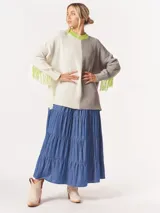 Buzo tejido oversized con bloques de color blanco y gris, cuello redondo en verde neón, tajos laterales y flecos verdes en las mangas.