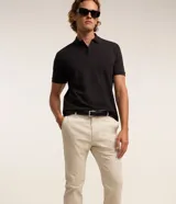 Pantalón slim de sarga color beige, de corte ajustado, con cierre frontal de botón y cremallera, y bolsillos laterales tipo cuchillo.