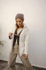 Campera de cuero color beige claro, estilo sobrecamisa o chaqueta ligera, con cuello camisero, cierre frontal con broches de nácar y dos bolsillos de parche en el pecho.