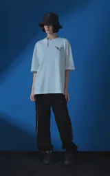 Remera blanca de corte oversize con cuello redondo y manga corta. Presenta una estampa gráfica en la espalda con diseño de palomas, flores y texto en español.