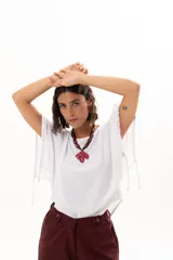 Blusa blanca de corte holgado y diseño minimalista, con mangas cortas tipo murciélago que presentan un detalle de fruncido lateral con cordón ajustable.