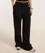 Pantalón wide leg negro confeccionado en algodón, con pliegues delanteros y cierre por botón y cremallera.