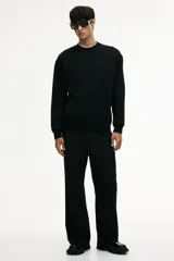Buzo negro de corte holgado, con cuello redondo y mangas largas.