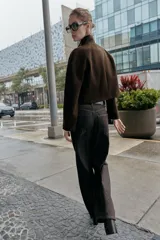 Chaqueta corta de paño en color beige, con cuello subido, manga larga y cierre frontal cruzado con botones oscuros. Presenta bolsillos delanteros de vivo.