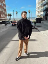 Campera de hombre color crema, de textura peluda, con cierre frontal, cuello alto, bolsillos laterales y un bolsillo impermeable negro en el pecho.