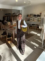 Cartera tipo hobo de gamuza color verde oliva, con cierre superior y correa ajustable al hombro.