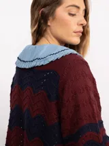 Campera de punto con cierre frontal bidireccional, mangas largas abullonadas y diseño calado con patrón de ondas en color negro con detalles brillantes.