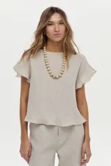 Blusa de lino color beige, de manga corta con volados, cuello redondo y espalda cruzada con volados.