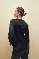Blusa negra de manga larga con cuello redondo y lentejuelas a tono.