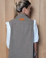 Chaleco de gabardina color tostado, con cuello camisero, cierre frontal con botones metálicos y dos bolsillos frontales con solapa.