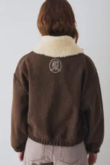 Campera tipo bomber de paño color marrón, con cierre frontal, puños y ruedo elásticos. Presenta un cuello de piel sintética desmontable en color crema y el logo de la marca bordado en el pecho.