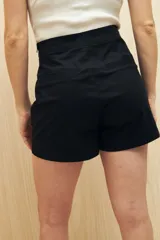 Short pollera color marrón de tiro alto, confeccionado en algodón. Presenta solapa frontal que simula una falda y bolsillos delanteros.