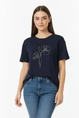 Remera de algodón color azul marino, con cuello redondo a la base y mangas cortas. Presenta un diseño floral minimalista bordado con studs dorados en el frente.