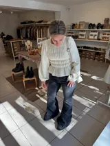 Blusa color manteca con diseño de frunces elásticos en el frente y la espalda, mangas largas abullonadas y terminación con volado en la cintura.