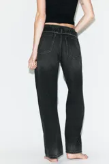 Jeans de mezclilla de tiro medio, corte wide leg y diseño relaxed. Presenta detalles rotos y desgastados en las piernas, y una cinturilla doblada superpuesta con trabillas y cierre frontal con cremallera y botón metálico.