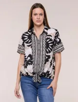 Camisa de gasa de manga corta con estampado en blanco, negro y beige, cuello con solapa, cierre frontal de botones y diseño con nudo en el ruedo.