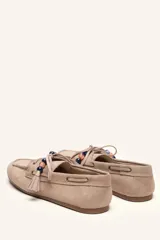Mocasín estilo náutico de gamuza marrón, con cordones de cuero, borla decorativa y cuentas de colores en el empeine.