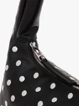 Bolso de hombro negro de efecto cuero, con forma curva y asa superior. Está completamente decorado con tachuelas metálicas redondas plateadas. Posee cierre superior con cremallera.