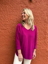 Sweater de hilo color fucsia, de corte holgado, con escote en V y mangas largas con vuelta.
