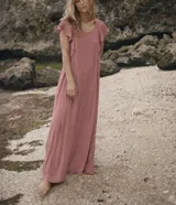 Vestido largo color rosado, con escote redondo y mangas cortas con detalles de volados en los hombros. Diseño fluido de corte holgado.