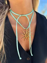 Collar con cordón ajustable color beige y dije de sol plateado.