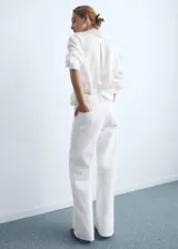 Jeans wide leg blancos de tiro alto con diseño de cinco bolsillos, trabillas para cinturón y bajo deshilachado. Cierre frontal con cremallera y botón.
