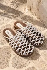 Sandalias Vdamianis tipo sueco, confeccionadas en 100% cuero, con base baja marrón y capellada de diseño entramado con nudos entrelazados en color blanco.