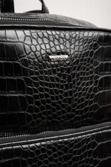 Mochila negra con textura símil cuero de cocodrilo, con dos compartimentos principales con cierre y asa de mano en la parte superior.