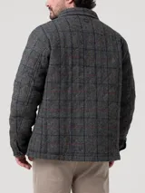 Chaqueta de lana Harris Tweed color gris con patrón de tartán, cuello camisero, cierre frontal de botones y bolsillos aplicados.