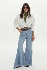 Camisa blanca de manga larga con flecos en la espalda y las mangas, confeccionada en mezcla de algodón, poliamida y elastano.