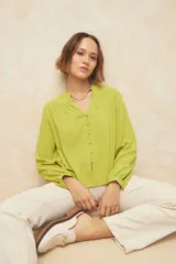 Camisa verde lima de manga larga con cuello mao y escote en V. Cuenta con botones forrados en la misma tela y puños elásticos.
