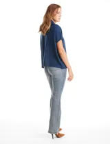 Cardigan de punto azul, con cierre frontal metálico completo, cuello con solapa y mangas cortas de sisa caída. Presenta un corte recto y holgado.