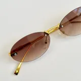 Lentes de sol con diseño ovalado y montura metálica dorada. Cuentan con cristales oscuros y protección UV400.