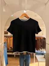 Remera tejida de manga corta con cuello redondo, confeccionada en una mezcla de poliéster, acrílico, poliamida y lana. Presenta un diseño de calce recto en color marrón con detalles de terminaciones en contraste de color blanco en el cuello, las mangas y el ruedo.