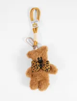Llavero con dije de oso teddy de peluche color beige con moño estampado animal print.