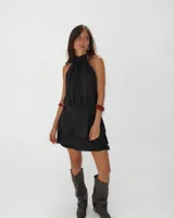 Vestido corto negro con cuello halter regulable, diseño sin mangas y falda con volados superpuestos.