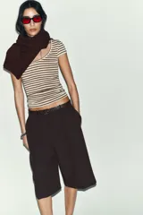 Camiseta de corte ajustado con escote redondo y manga corta, confeccionada en tejido de punto con lana. Presenta un diseño de rayas horizontales en tonos beige y marrón.