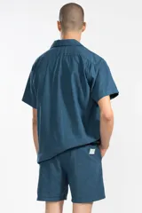 Camisa azul con bordado de flores en el pecho, de corte cuadrado y calce relajado. Confeccionada en Italia en mezcla de lino y algodón. Tiene cuello tipo camp y cierre con botones de coco grabados con el logo.