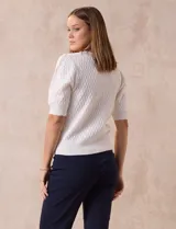 Cárdigan blanco tejido con escote en V, abertura frontal con botones y mangas cortas abullonadas con puño.