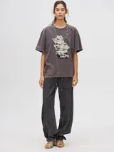 Remerón oversize de algodón, corte cuadrado y básico, color gris oscuro con efecto gastado. Estampa frontal de una figura abstracta o mano en tonos claros y texto en un idioma asiático en la manga.