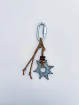 Charm para bolso o accesorios con mosquetón metálico, tejido de macramé en cordón negro y dijes de cerámica esmaltada en tonos violeta y celeste.