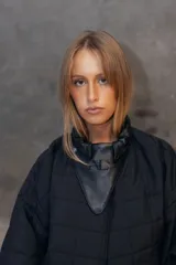 Campera puffer de diseño matelaseado en rombos, color beige. Presenta cuello alto, cierre frontal y solapa triangular decorativa con logo bordado. Posee mangas largas con puños elastizados y ruedo ajustado tipo bomber.