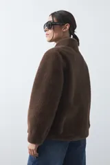 Tapado de piel sintética color marrón, de corte recto y cuello clásico. Presenta cierre frontal con botones y diseño de textura suave y voluminosa.