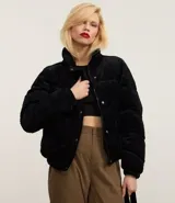 Campera puffer de mujer con diseño acolchado y textura acanalada tipo cotelé. Presenta cuello alto, cierre frontal con botones a presión y puños elásticos.
