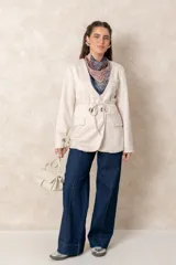 Chaquetón color beige de corte recto y largo, con cierre frontal mediante botones y lazo ajustable en la cintura. Presenta cuello en V, bolsillos laterales con solapa y mangas largas.